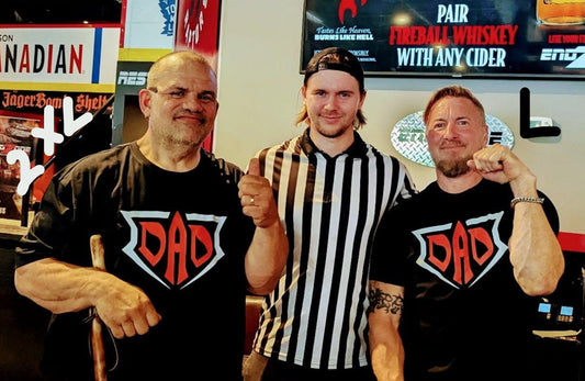 Three men posing together in a bar setting, two wearing 'DAD' t-shirts.