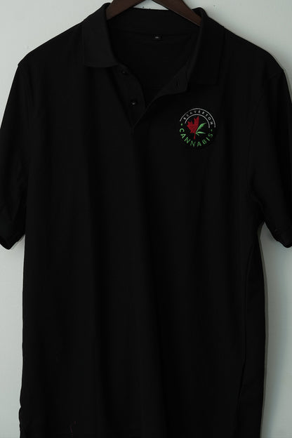 Black polo shirt with a logo on a hanger against a white wall