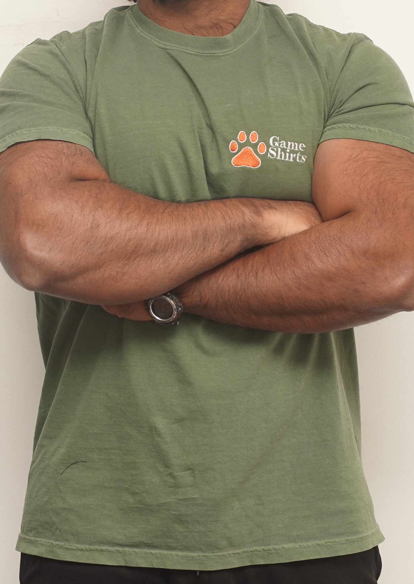 Person wearing a green t-shirt and black shorts with 'Game Shirts' logo on a white background